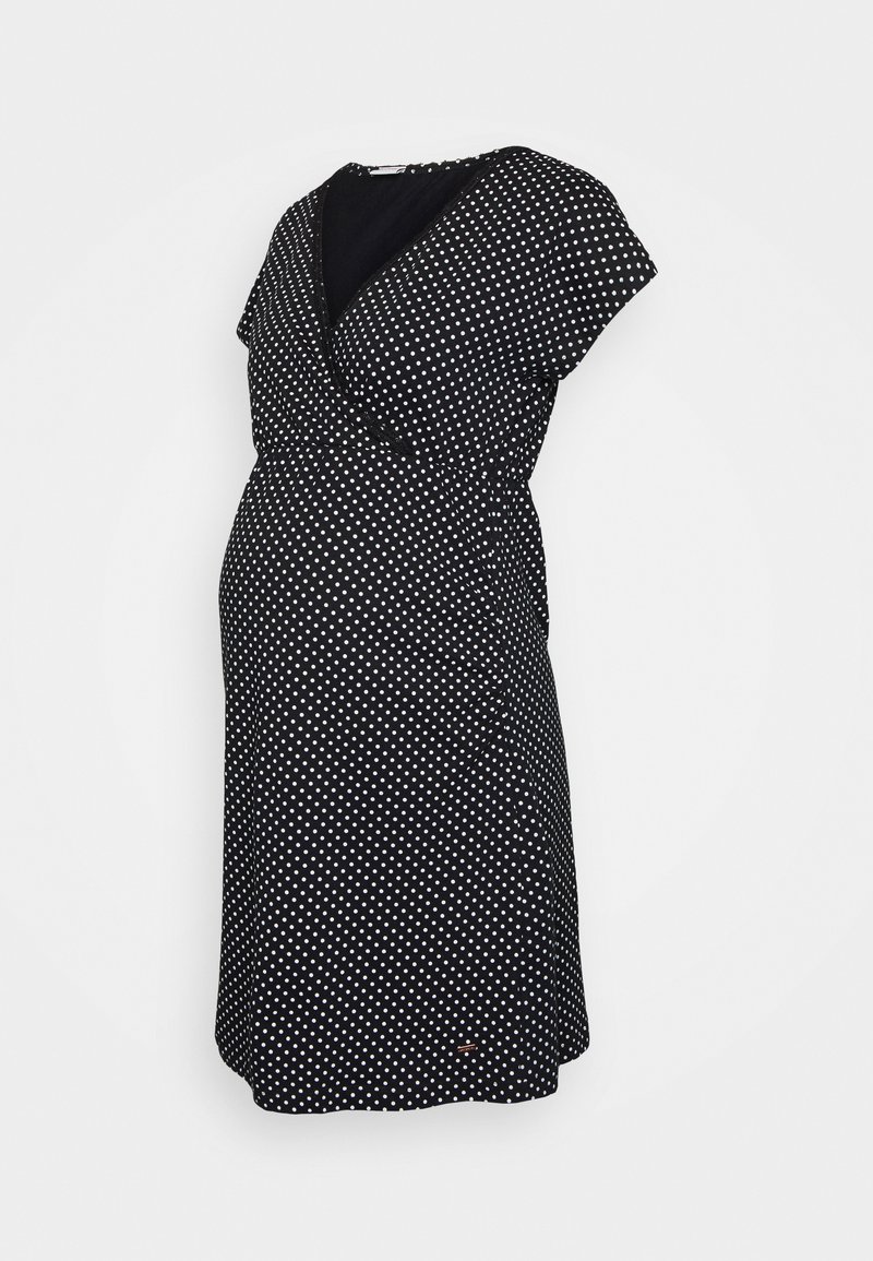 Czarna sukienka o kroju kopertowym w białe kropki, krótki rękaw, dekolt w serek oraz zwiewny materiał zaprojektowany z myślą o komforcie w czasie ciąży.