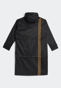 Černý dlouhý kabát s kapucí a třemi vertikálními žlutými pruhy na jedné straně. Vyrobeno z hladkého, lehkého materiálu s volným střihem.