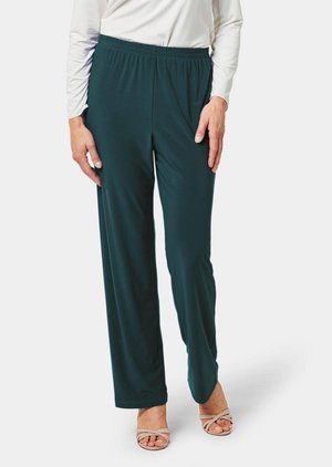 Groene broek met elastische tailleband in een gladde stof, met een ontspannen pasvorm en volledige lengte, gecombineerd met beige sandalen met bandjes.