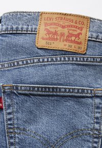 Lichtblauwe denim jeans met een achterzak waarin het leren label van Levi Strauss & Co. zichtbaar is, met maat W32 L32 en model 511.