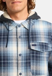 Blue and white plaid flannel shirt with a gray hood. Features a button closure, chest pocket, and soft fabric texture.