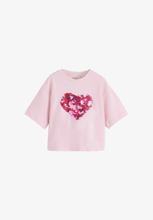 Jasnoróżowy t-shirt z krótkim rękawem, okrągłym dekoltem i dużym sercem z czerwonych i różowych cekinów na przodzie.