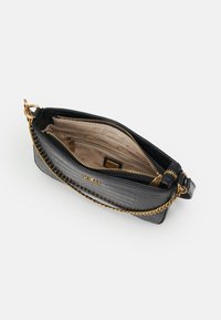Sac en simili cuir crocodile noir avec une bandoulière en chaîne dorée et des fermetures éclair. L'intérieur est doté de plusieurs poches et d'une doublure beige lisse.