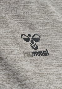 Grå tekstureret stof med et sort logo af en stiliseret bi og ordet "hummel" nedenunder.