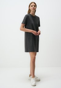 Abito a t-shirt grigio in misto cotone con scollo rotondo e maniche corte, che arriva sopra il ginocchio, abbinato a sneaker bianche.