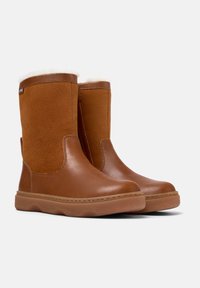 Bottines en cuir marron avec une tige en daim, doublure blanche moelleuse, bout rond et semelle en caoutchouc. Caractéristiques de couture minimale et texture lisse.
