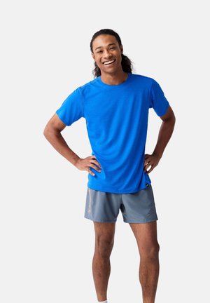 Blaues Sport-T-Shirt mit kurzen Ärmeln, kombiniert mit grauen Shorts. Das Shirt hat einen Rundhalsausschnitt und eine glatte Textur.