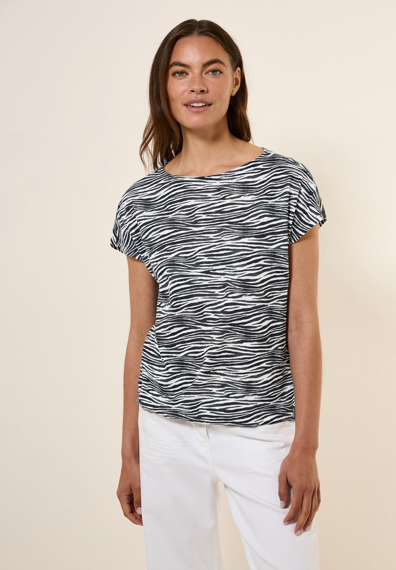 Schwarz-weißer gestreifter T-Shirt mit kurzen Ärmeln und weitem Halsausschnitt, aus leichtem Stoff gefertigt, kombiniert mit weißen Hosen.