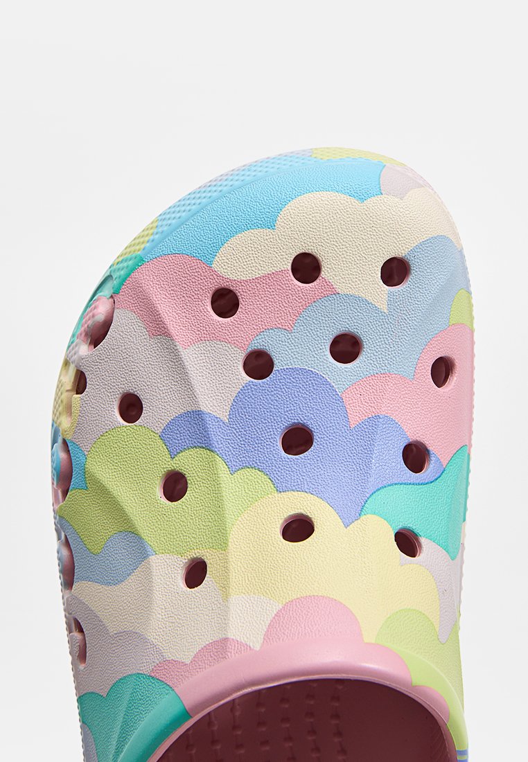 Zoccolo colorato con pattern di nuvole, realizzato in materiale leggero e testurizzato; presenta fori di ventilazione e una base rosa con finitura liscia.