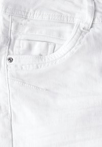 Tissu en denim blanc avec une poche avant dotée d'un détail en métal argenté et d'une texture diagonale subtile. Le design global est simple et épuré.