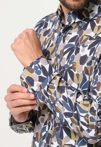 Overhemd met knopen in een bloemmotief met donkerblauw, olijf, bruin en crèmekleuren; lange mouwen met knoopmanchetten en een klassieke kraag.