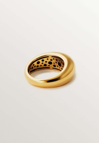 Anillo de oro con un exterior suave y un interior perforado. Diseño redondeado con un acabado pulido, que presenta recortes circulares para aportar textura.