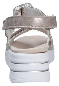 Silver suede sandals featuring a wide ankle strap, a white wedge heel with silver accents, and a soft beige insole.