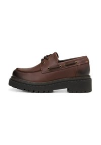 Chaussure en cuir brun à lacets avec une pointe arrondie, semelle en caoutchouc noir épais, œillets en métal et des détails de couture le long de la tige.