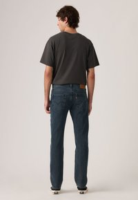 Γκρι κοντομάνικη μπλούζα συνδυασμένη με σκούρο μπλε τζιν παντελόνι, με πίσω τσέπες και καφέ δερμάτινο ταμπελάκι κοντά στη μέση.