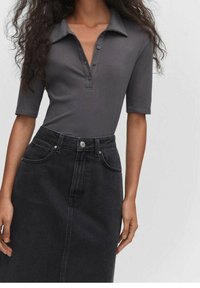 Graues geripptes Poloshirt mit Kragen und Knopfleiste; kombiniert mit einem hochgeschnittenen schwarzen Jeansrock mit Fronttaschen.