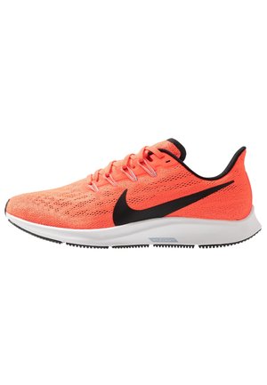 Jasno pomarańczowy but do biegania Nike z czarnym logo swoosh, białą środkową podeszwą, czarną podeszwą zewnętrzną i pomarańczowymi sznurowadłami.
