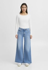 Light blue high-waisted jeans with a wide-leg design, made from denim, featuring a front button closure and subtle fading.