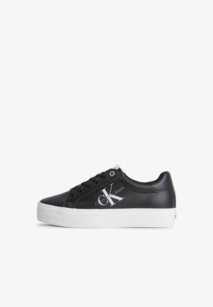 Sort lav sneaker med hvid tyk sål, sorte snørebånd og Calvin Klein Jeans-logo på siden.