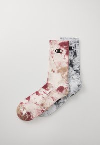 Pamut keverék zokni, amely rózsaszín és szürke árnyalatokban tye-dye mintával rendelkezik, mindkét zoknin kontrasztos fekete szem grafikával.
