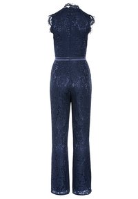 Jumpsuit de encaje navy con detalles transparentes, cuerpo ajustado, diseño sin mangas con picos, cintura ceñida y perneras acampanadas. Cierre de cremallera en la parte posterior.