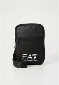 Črna najlonska torbica čez ramo z žepom z zadrgo spredaj, na sprednji strani z belim logotipom "EA7 EMPORIO ARMANI" in nastavljivim trakom.