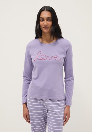 Mujer con blusa de manga larga lila con bordado rojo de "amor" y corazón, combinada con pantalones a rayas horizontales lilas y blancas.