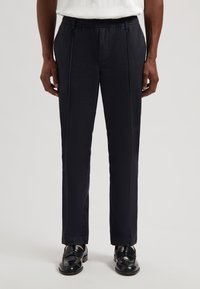 Marineblå bukser med teksturert finish, elastisk midjeb�ånd, rett snitt og sidelommer. Brukes med svarte loafers for et polert utseende.