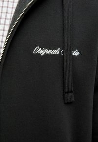 Crna zip-up hoodie s teksturiranim materijalom, s našivenim "Originals" logotipom u bijeloj boji i podesivim vezicom na kapuljači.
