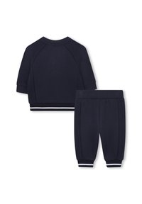 Marineblauwe twee-delige outfit met een kortemouwen blouse met een geribbeld textuur en bijpassende joggerbroeken met gestreepte accenten aan de boorden.