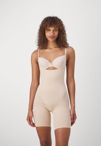 Beige shapewear bodysuit with molded cups, adjustable straps, and a mid-thigh length. Smooth texture with a subtle sheen.