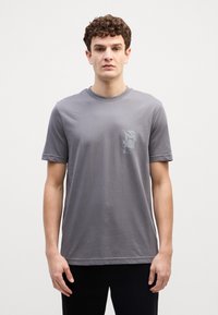 Grijze T-shirt met korte mouwen van zachte katoen, met een kleine grafische print op de linkerborst en een klassieke ronde hals.
