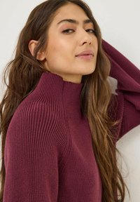 Maglione di cashmere bordeaux a coste con lavorazione in rilievo, body aderente e maniche allungate, che presenta un design accogliente e caldo.