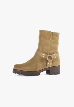 Suede mid-calf tan boot with black chunky sole, silver ring and rivet strap detail, and low block heel.