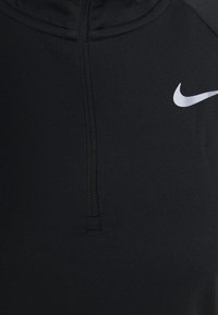 Lähenemine mustale kangale, millel on keskel õmblus ja paremal küljel valge Nike swoosh logo.