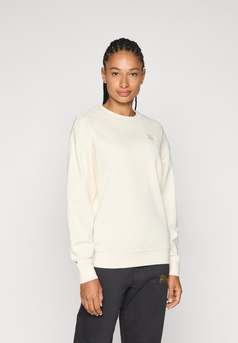 Cremefarbener Sweatshirt aus weichem Stoff, mit einem runden Ausschnitt und gerippten Bündchen. Kleines Logo-Detail auf der oberen linken Brust.
