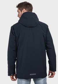Marineblaue Kapuzenjacke aus leichtem Material, mit gerader Schnittführung, verstellbaren Manschetten und einem dezenten Logodetail am hinteren Saum.