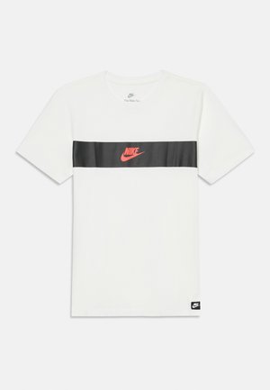 T-shirt Nike blanc à manches courtes avec une bande noire horizontale sur la poitrine, présentant un logo Nike rouge et une petite étiquette Nike noire au bas.