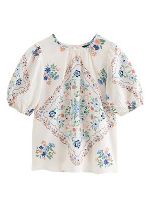 Blouse blanche à manches bouffantes avec des motifs floraux bleus, verts et pêche disposés en losange central et en grappes dispersées.