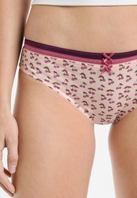 Różowe bawełniane majtki z wzorem w czereśnie, z ciemnoróżową elastyczną gumką w talii i małą kokardką z przodu.