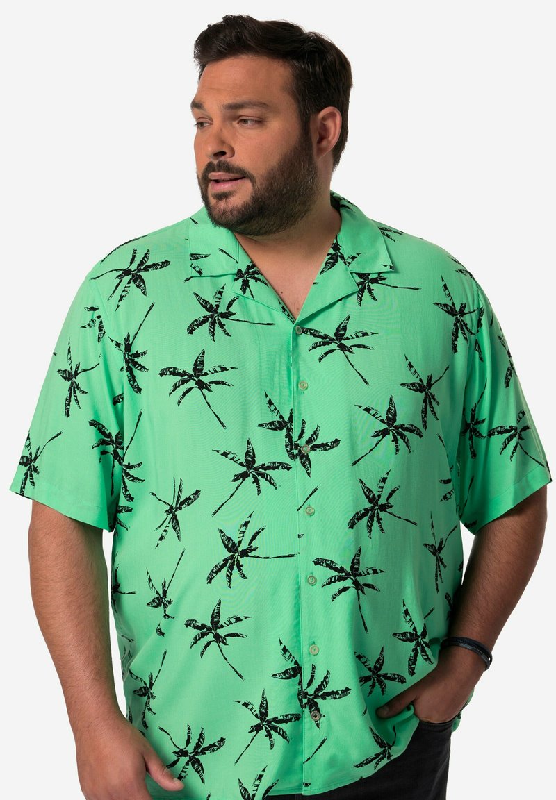 Krátký rukáv, košilové tričko ze světle zelené látky s černými vzory palem. Výrazný design límce a hladká textura.