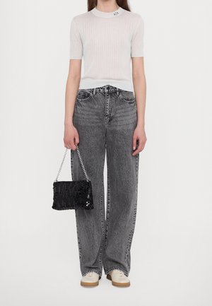 Biały prążkowany top z krótkim rękawem, szare dżinsy o szerokich nogawkach oraz czarna torebka z cekinami i srebrnym łańcuszkiem. Sneakersy z beżowo-brązową podeszwą.