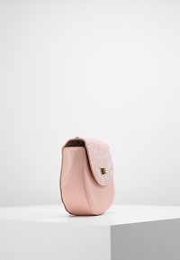 Różowa skórzana torebka o zaokrąglonym kształcie, z teksturowaną różową klapą i złotymi detalami. Gładka powierzchnia o subtelnym połysku.
