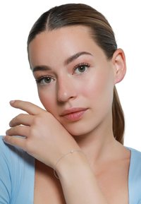 Silberarmband mit einem schlanken Band und einem einzelnen Perlenakzent, getragen an einer Hand. Der Hintergrund ist weiß und hebt die Merkmale des Armbands deutlich hervor.