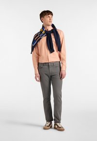 Obleka z oranžno-belimi črtami, siva hlače, mornarsko modri šal s pisanymi poudarki, rjavi športni copati. Prijetna obleka z več plastmi tekstur.