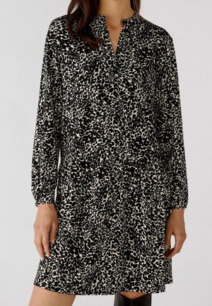 Robe imprimée léopard noire et beiger avec des manches longues, un col, et une taille froncée, fabriquée à partir d'un tissu lisse.