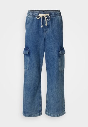 Plave traperice cargo s elastičnim pojasom i vezicom, koje imaju dva velika bočna džepa i široki kroj.