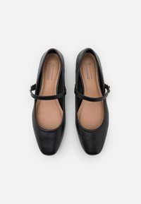 Mustand vegan nahast ballerina kingad ümarate varvastega, sääre rihmaga, sileda tekstuuriga ja külgedel peente õmbluste detailidega.