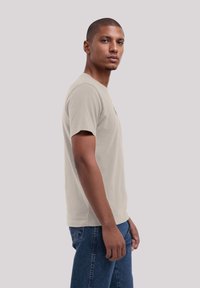 Helle beige Kurzarm-T-Shirt aus weicher Baumwolle, mit einem Rundhalsausschnitt und einem lässigen Schnitt, kombiniert mit blauen Jeans.