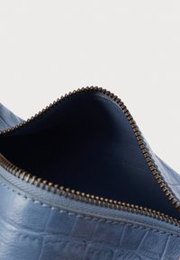 Modrá kožená bota s reliéfním krokodýlím vzorem, vybavená bronzovým zipem v otevírání, s hladkou vnitřní texturou.